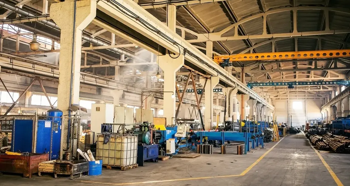 Interior de fábrica com ponte rolante e equipamentos ao fundo